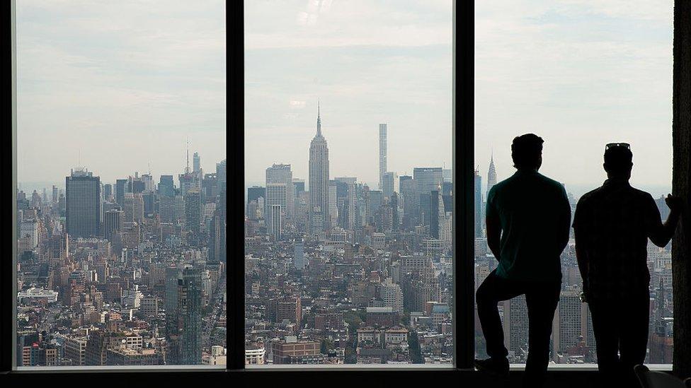 Two men look out the window of the 63rd floor of One World Trade Center toward Manhattan