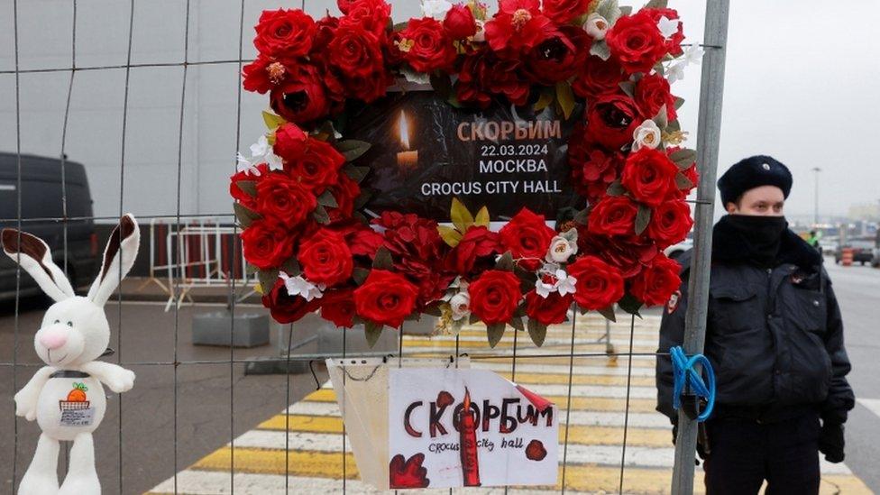 A police officer stands next to a makeshift memorial to the victims of a shooting attack at the Crocus City Hall concert venue