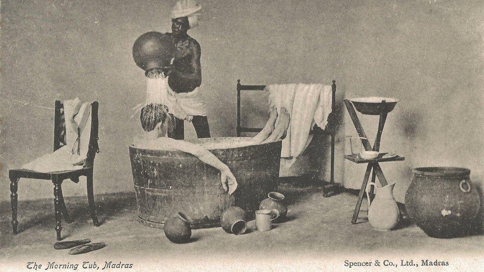 A postcard showing an Indian domestic help pouring water over a white man while he bathes in a tub.