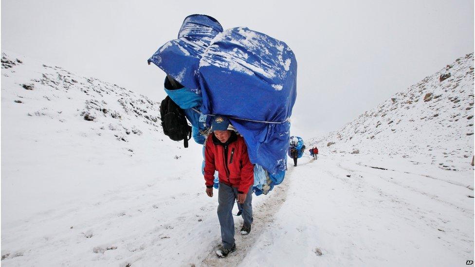 A porter walks with a massive load towards Everest Base camp