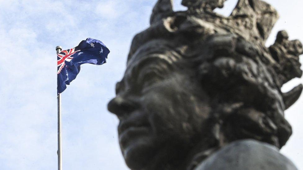 Statue of Queen Elizabeth next to an Australian flag