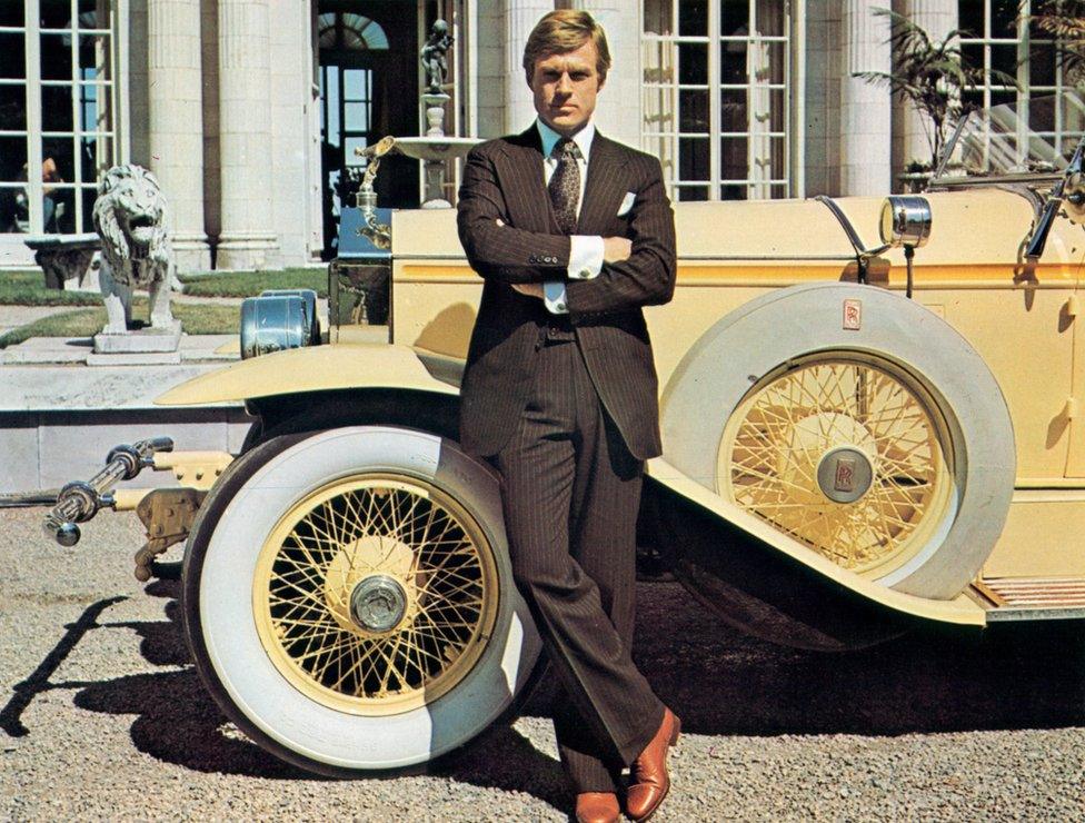 Robert Redford leaning against luxurious car in a scene from the film "The Great Gatsby", 1974.