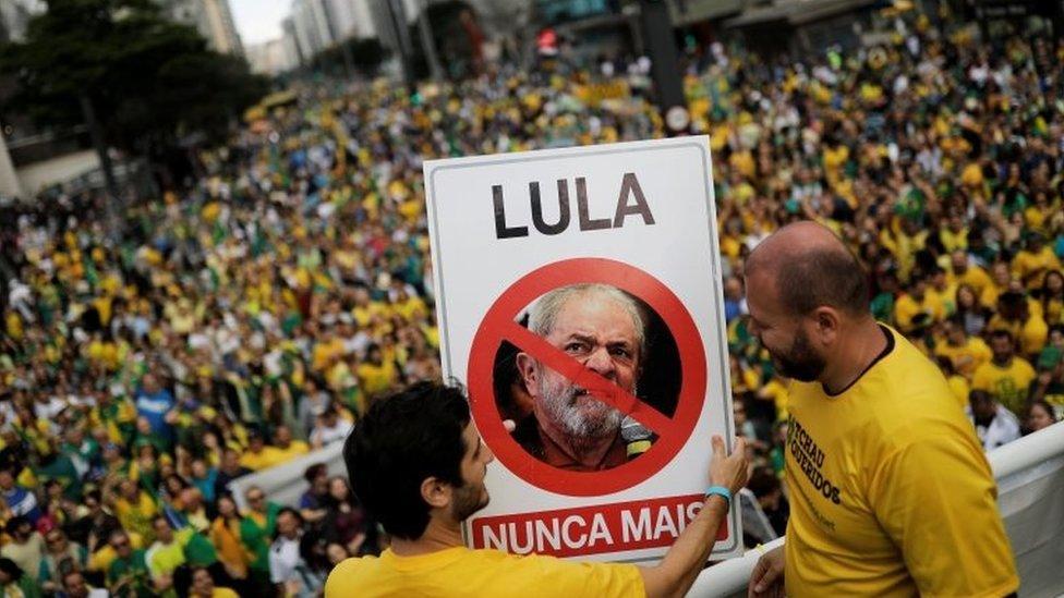 Supporters of Jair Bolsonaro hold a sign with the image of former Brazilian President Luiz Inácio Lula da Silva reading "Lula, never again"