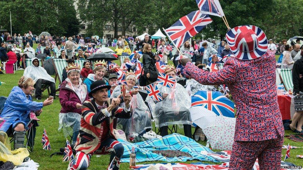 Joseph Afrane, 52, in Union Jack clothing waves flags as members of the public in Green Park gather for a picnic and watch The Queen"s Patronage on a big screen during "The Patron's Lunch" celebrations