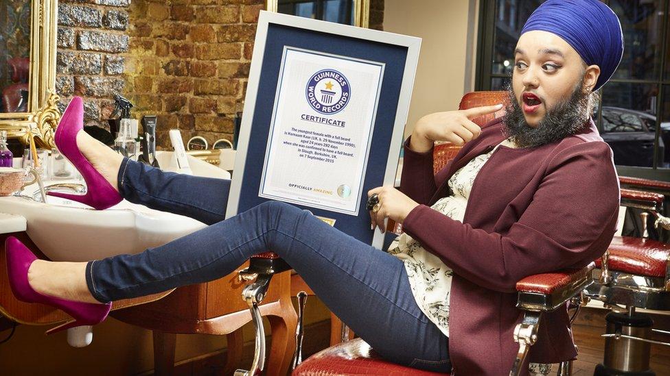 Young woman with full beard holding certificate.