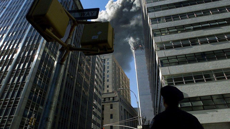 A police office looks up at the north tower of the World Trade Center.