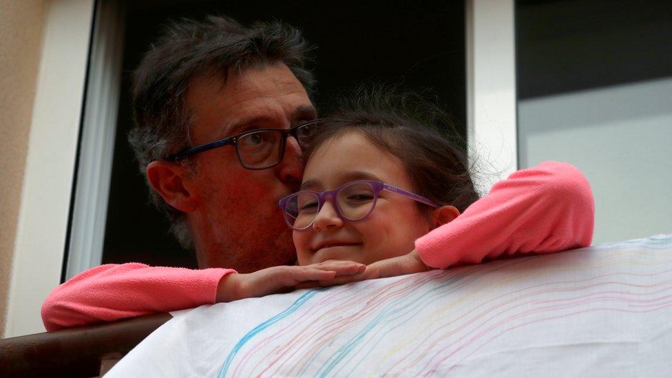 A man kisses his daughter after applauding in support of health workers,