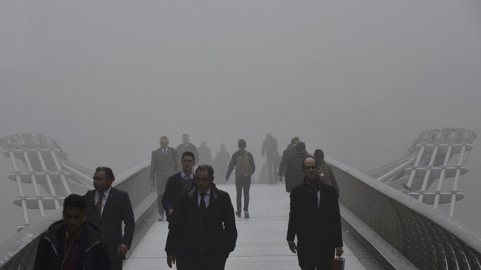 Commuters walk across Millennium Bridge over the Thames