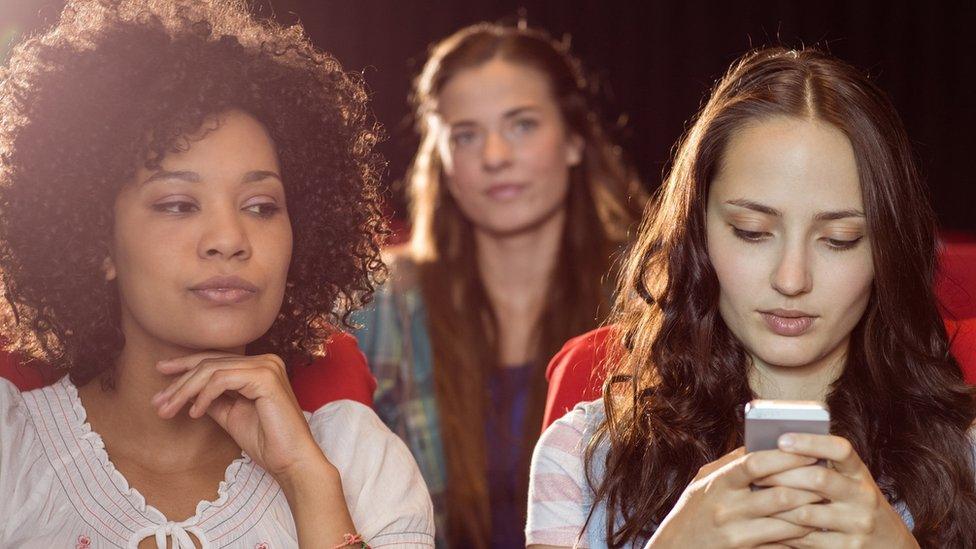 A woman texting in a cinema