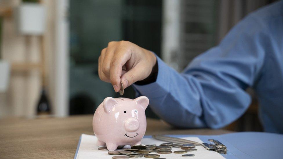 Man putting a coin into a pink piggy bank