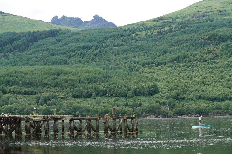 A paddleboarder with The Cobbler in the background