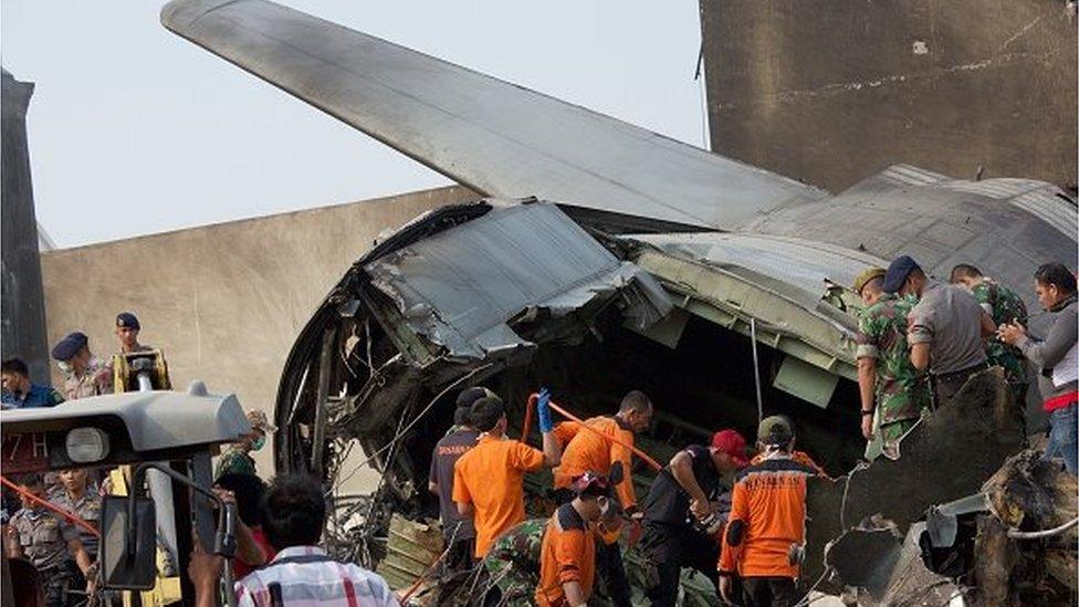 Military personnel and search and rescue teams comb through the wreckage of a military transport plane which crashed into a building on June 30, 2015 in Medan, Indonesia.