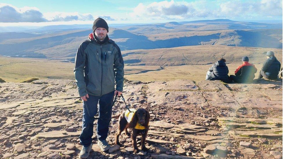 Gary Stretton standing on a hill with his dog beside him