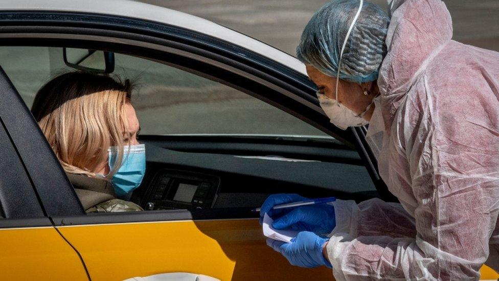 A medical staff wearing a protective suit speaks with a woman near a testing point for Covid-19 in central Moscow