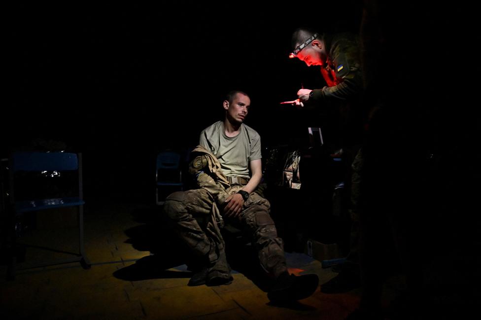 A medic speaks with an injured Ukrainian serviceman inside a frontline medical stabilisation point, amid Russia's attack on Ukraine, in Ukraine July 27, 2023.