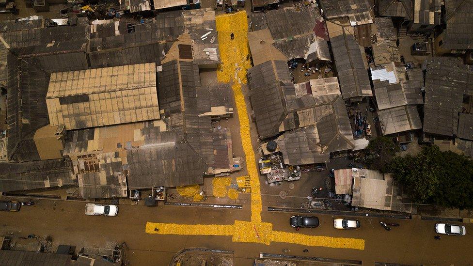 Aerial shot of yellow tapestry created by artist Serge Attukwei Clottey on roads in La - Accra, Ghana