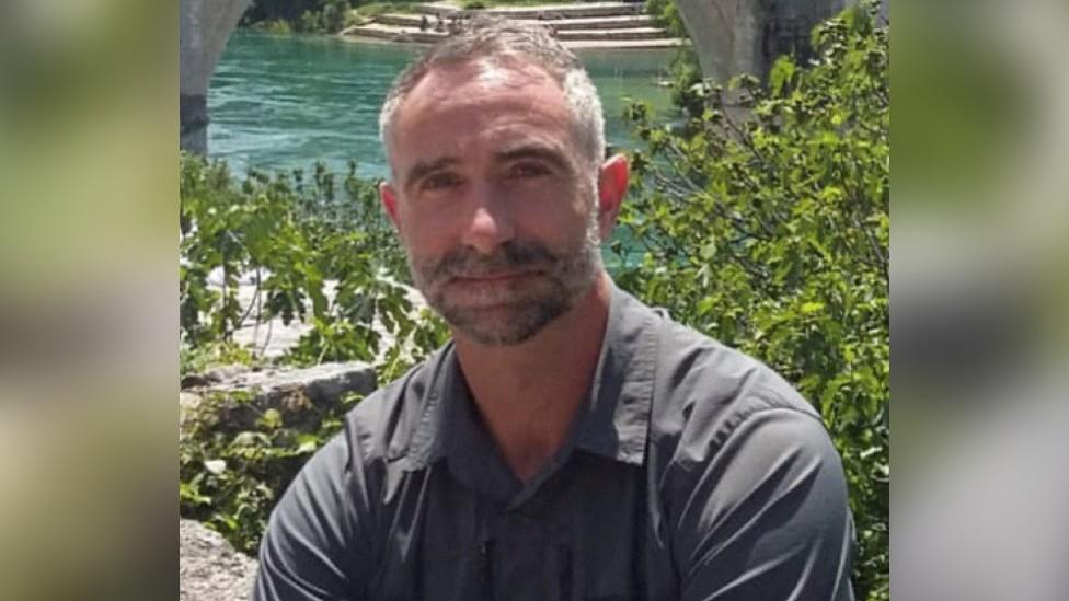 James Kirby in front of plants and an outdoor pool