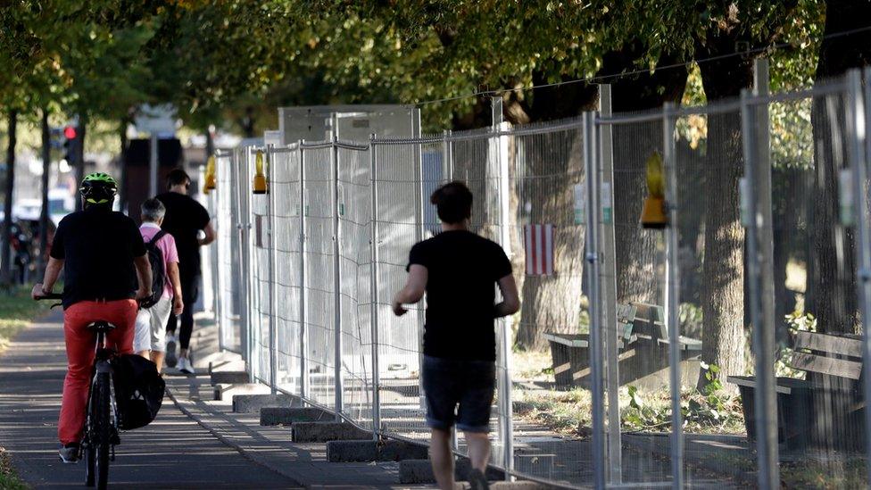 People make their way besides a fence at the "Theresienwiese", the area of the Oktoberfest, in Munich, Germany, Wednesday, Sept. 14, 2016