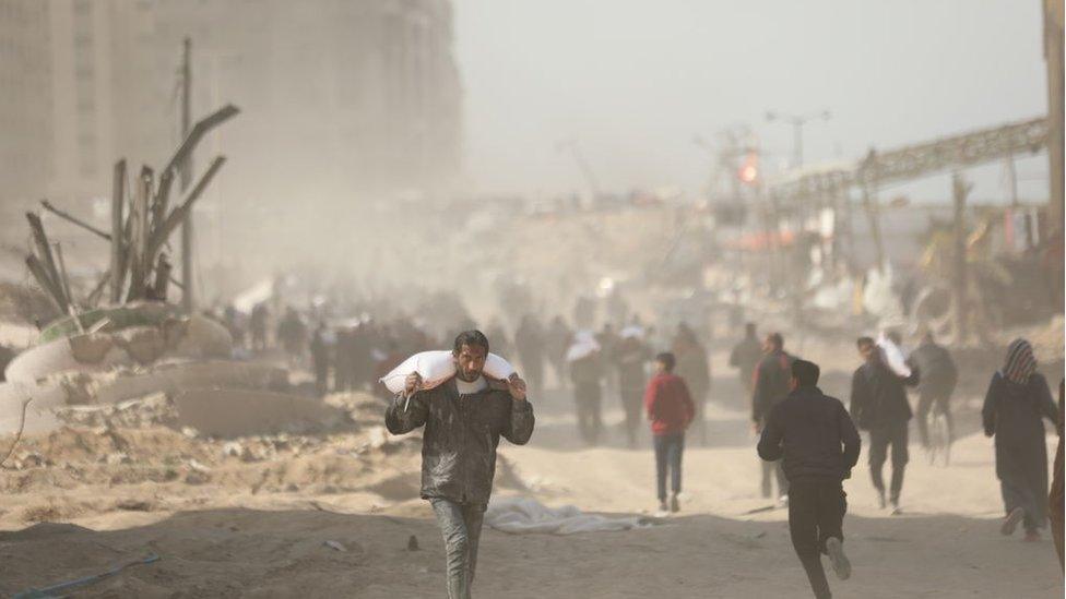 man carries flour from truck west of Gaza city on 6 March