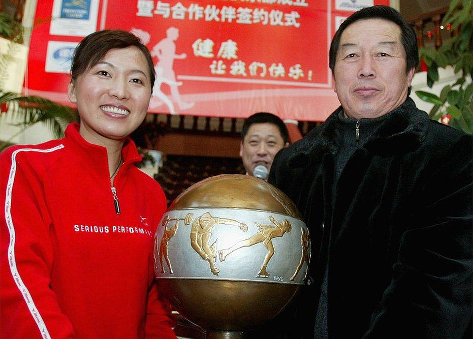 Olympic long-distance running champion Wang Junxia (L) poses for pictures holding an award with her teacher, former China track coach Ma Junren during an opening ceremony of Wang's Running Club on 25 January 2005 in Shenyang of Liaoning Province, China.