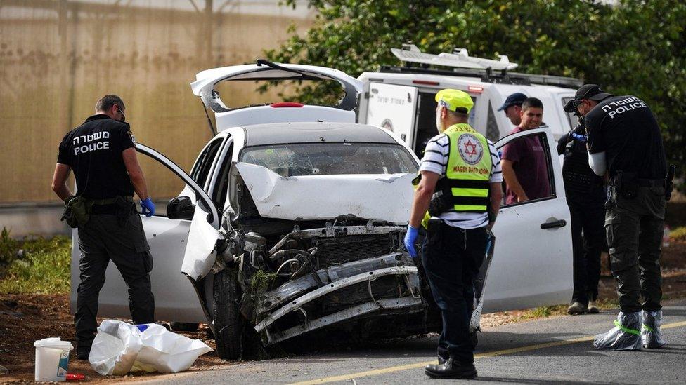 Israeli medics and police check a damaged car at the scene of a shooting attack in the Jordan Valley in the Israeli-occupied West Bank (7 April 2023)