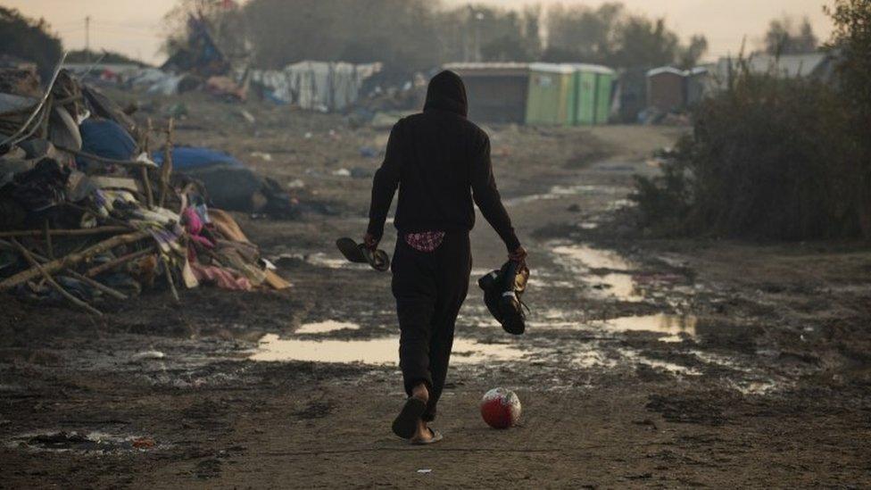 A migrant kicks a ball as he past tents destroyed in the makeshift migrant camp known as the jungle near Calais (28 October 2016)