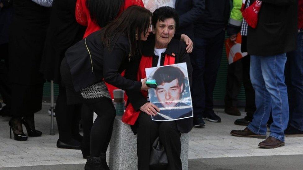 A woman holds an image of a victims of the 1989 Hillsborough disaster, as she reacts following the conclusion of the inquest into the disaster