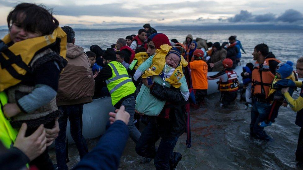 Migrants, including young children, being helped as they arrive on the Greek island of Lesbos