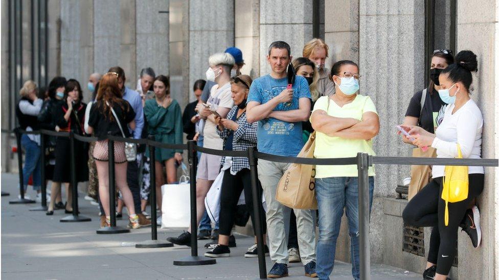 Shoppers queue to enter a discount store in New York