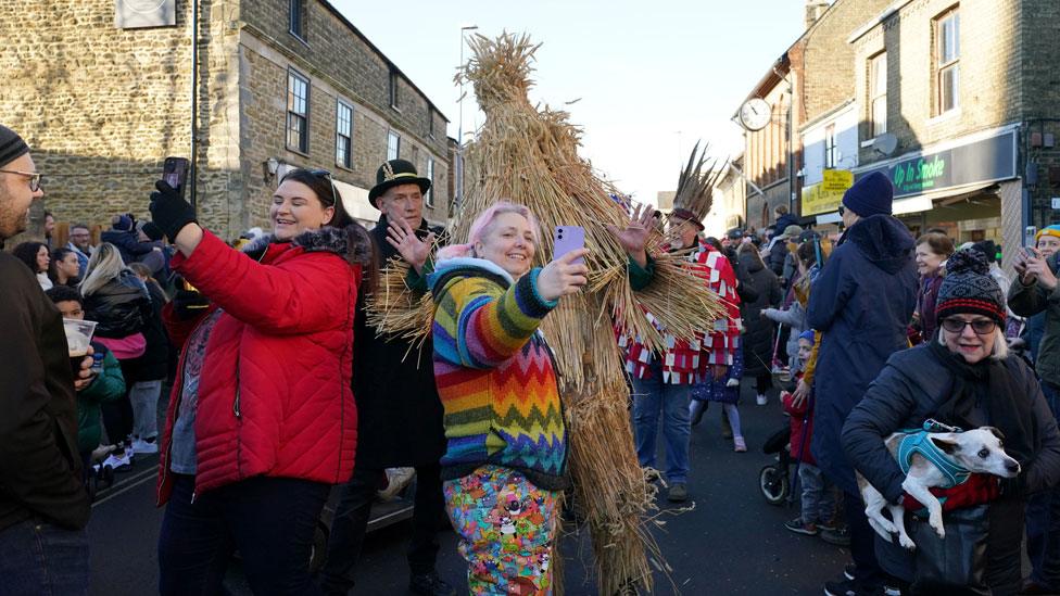 Women grabbing selfies with straw bear and keeper, Whittlesey, 2024