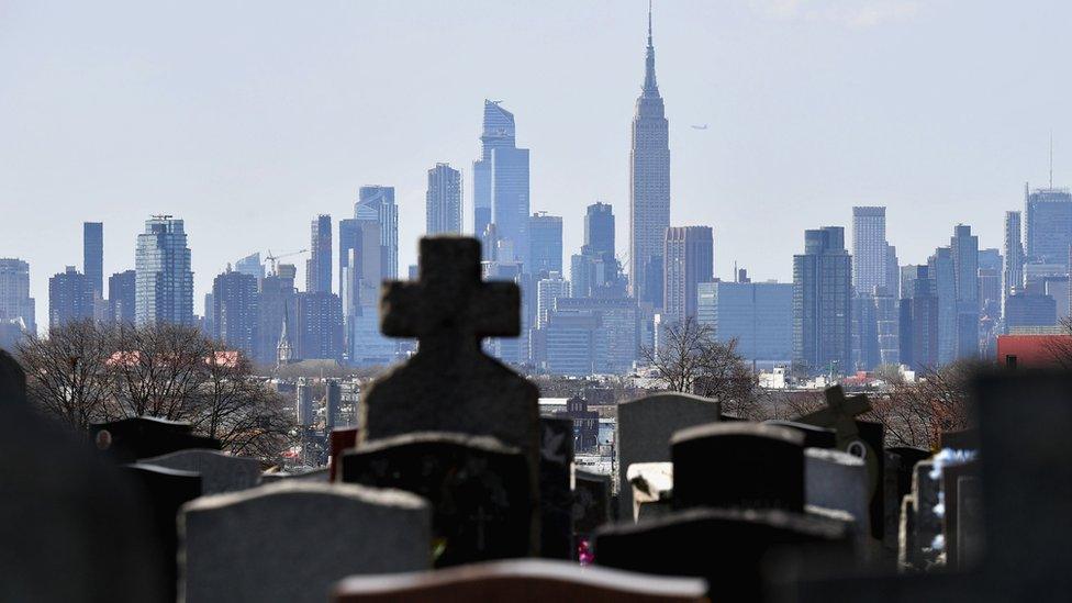 Gravestones from a cemetery are seen with the Manhattan skyline