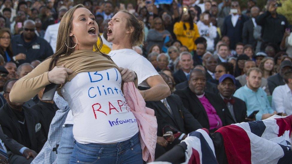 Demonstrators wearing shirts reading 'Bill Clinton Rapist' protest as US President Barack Obama speaks during a Hillary for America campaign event in Greensboro, North Carolina, October 11, 2016