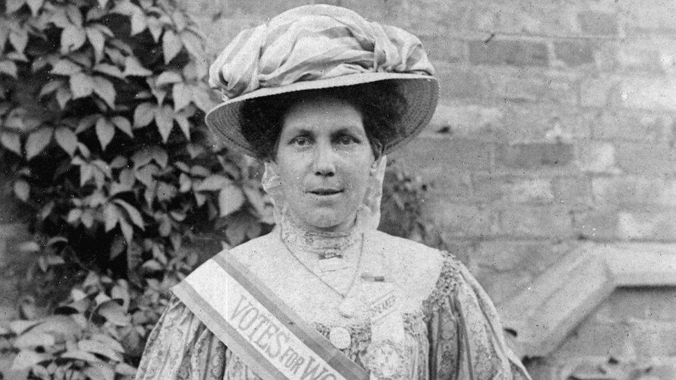 Alice Hawkins with a Votes for Women sash and poster