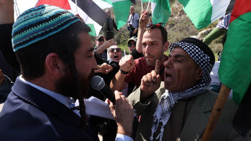 A Palestinian man and an Israeli peace activist argue with an Israeli settler at the entrance of town of Hawara, in the occupied West Bank (3 March 2023)