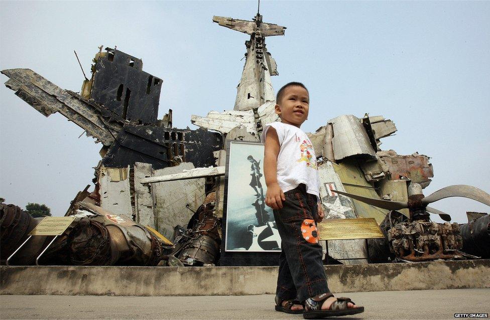 Child stands before remains of US aircraft, including part of a B-52 shot down over Vietnam