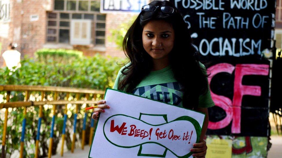 A woman holds a #HappyToBleed poster