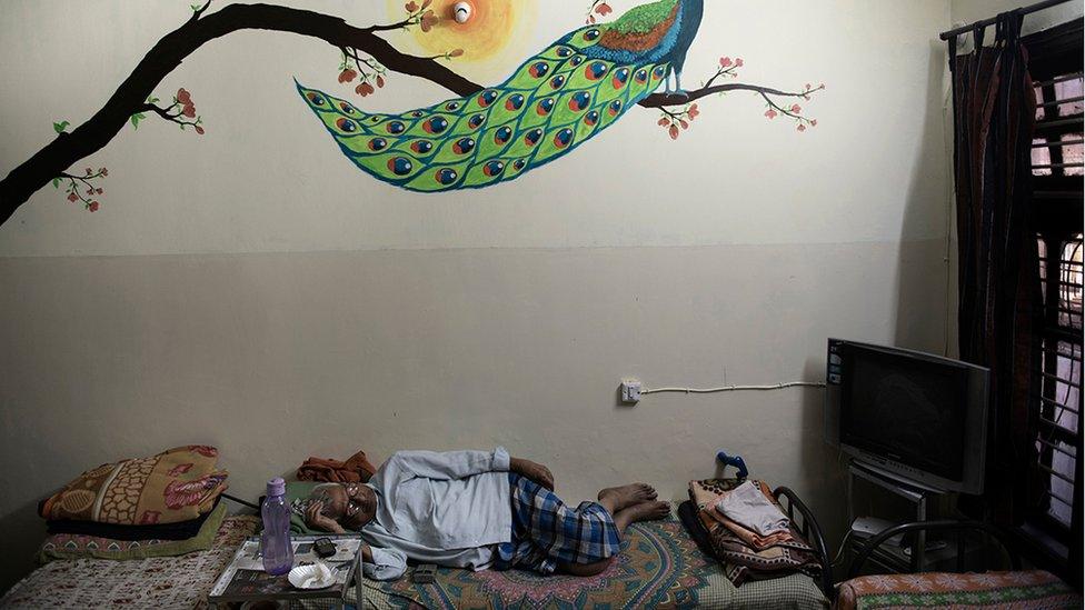 Mr Parameswar lying down on a bed in his room at the care home