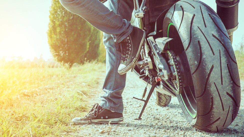 A motorcyclist in jeans and trainers