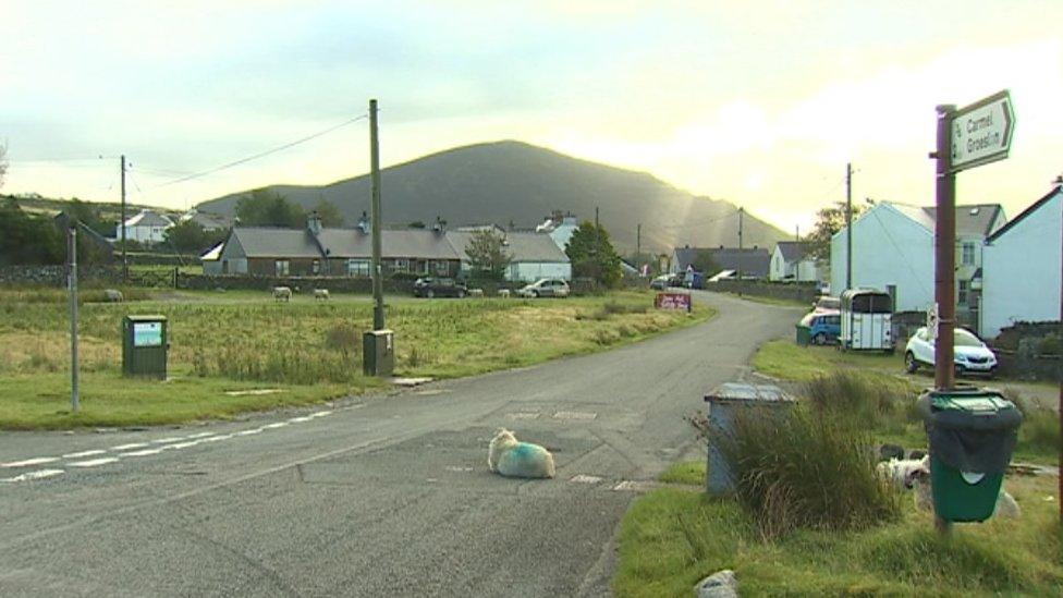 A sheep sits in the road in the village