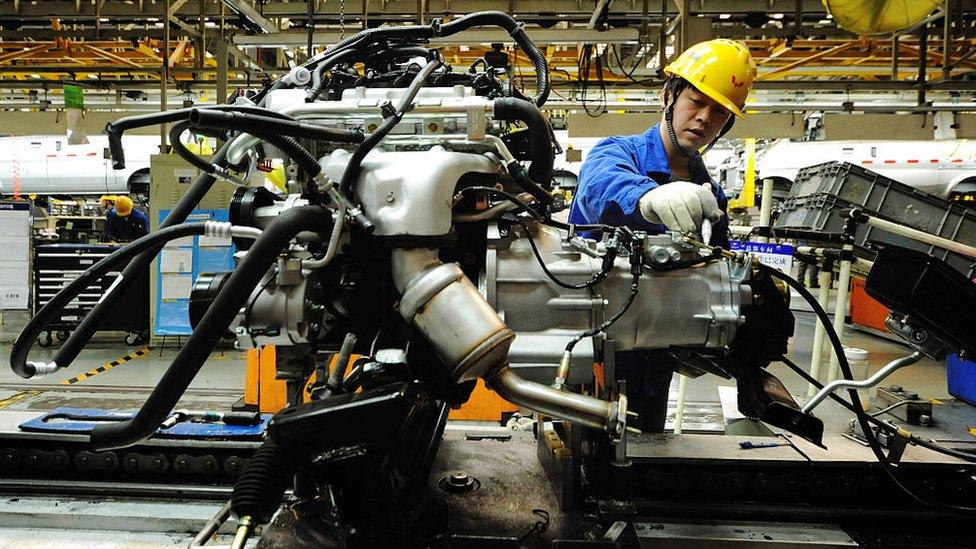 An employee works on an engine at the assembly line of a car factory in Qingdao, eastern China's Shandong province