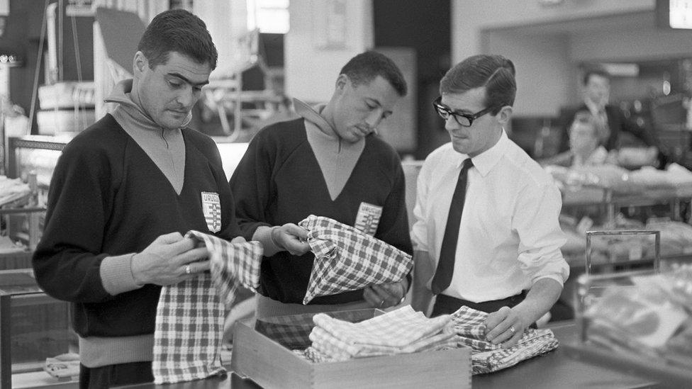 Uruguay 1966 World Cup squad members Walter Taibo and Julio Cortes examine cuts of cloth during a visit to an English textile factory on 5 July 1966, a week before the tournament began