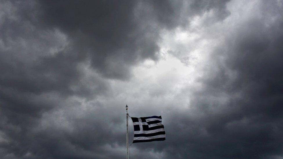 Greek flag against backdrop of stormy sky