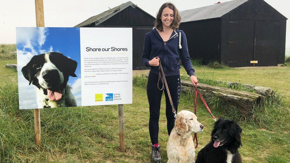 Dog walker next to large warning sign