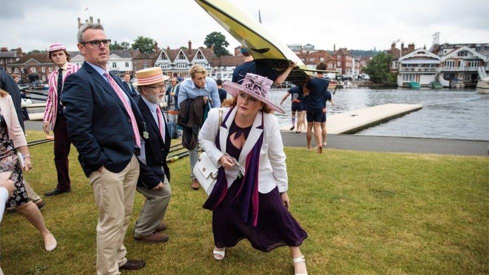 Spectators duck under rowing boats