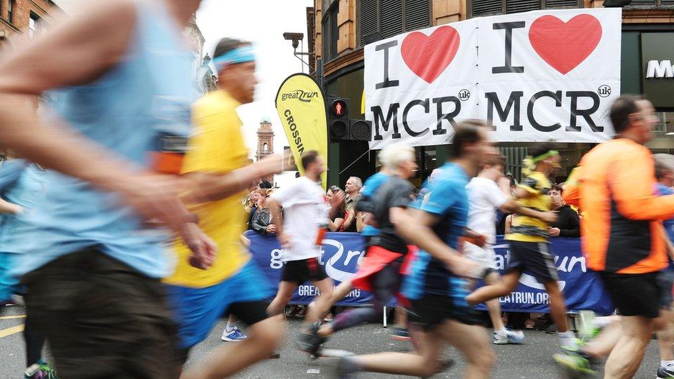 Crowds run in front of "I heart Manchester" signs