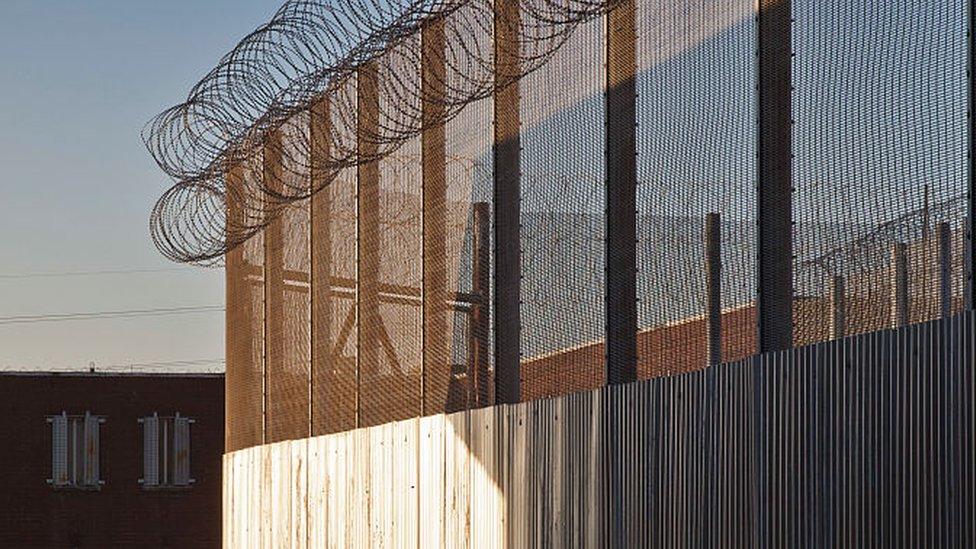 The sun shining on one of the inner perimeter fences at HMP Featherstone