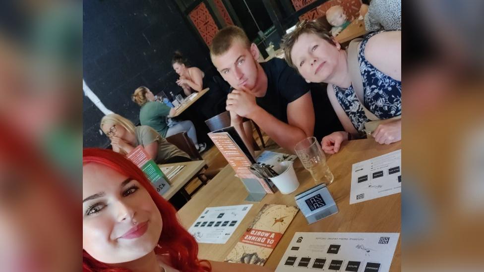 Ben, his mum Sharon and sister Izzy sat at a table in a restaurant