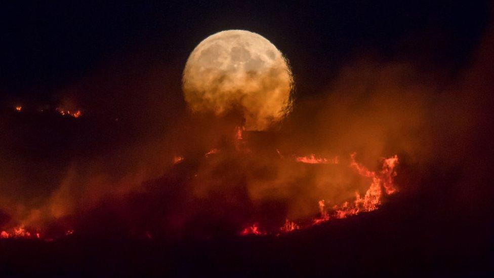 The full moon rises behind burning moorland as a large wildfire sweeps across the moors between Dovestones and Buckton Vale in Stalybridge, Greater Manchester on June 26, 2018 in Stalybridge, England.