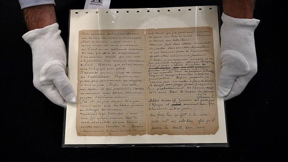 An auctioneer holds a letter co-written by Dutch painter Vincent Van Gogh and French painter Paul Gauguin