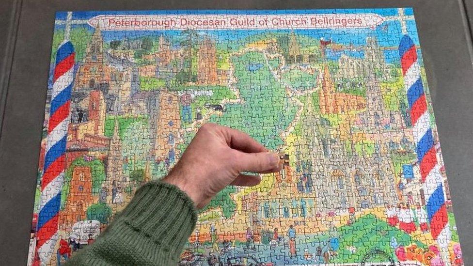 Jigsaw showing drawings of churches and the name of the Guild. A hand is inserting the last piece.